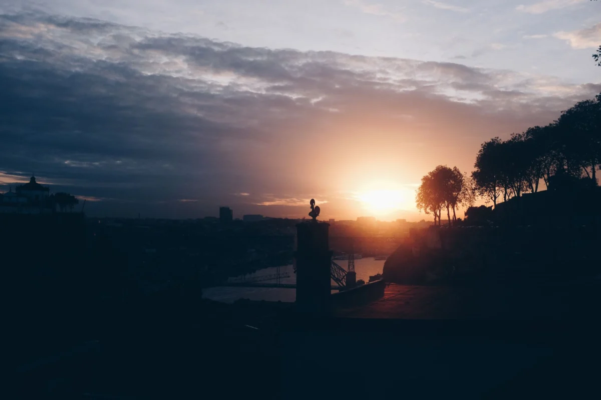 Golden sunset over Porto's Douro River with city lights
