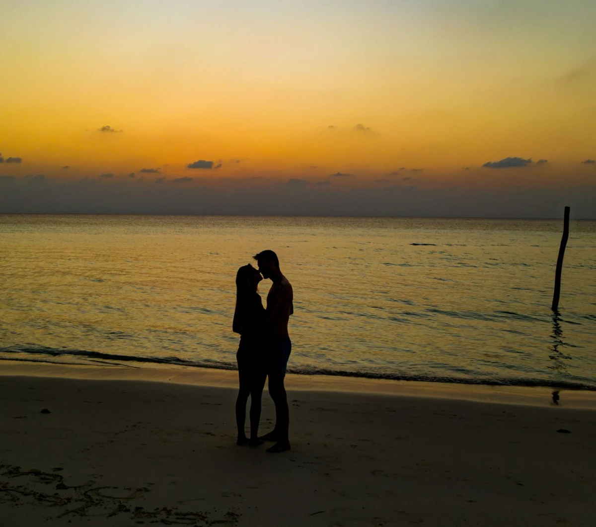 Couple enjoying a sunset on Dhigurah beach for first-time visitors