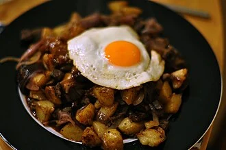 Steak with fried eggs, potatoes, and parsley sauce